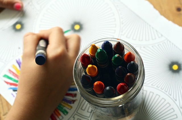 Bild på ett barn som ritar med kritor och färger.